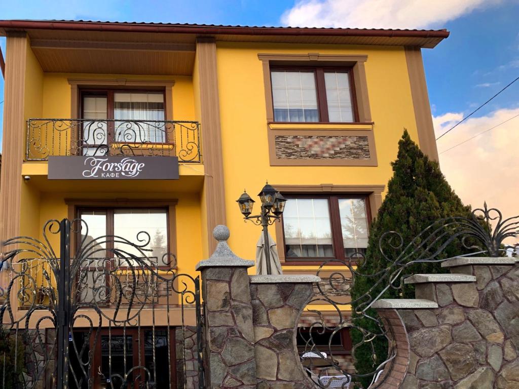 a yellow house with a fence in front of it at Forsage Hostel in Uzhhorod