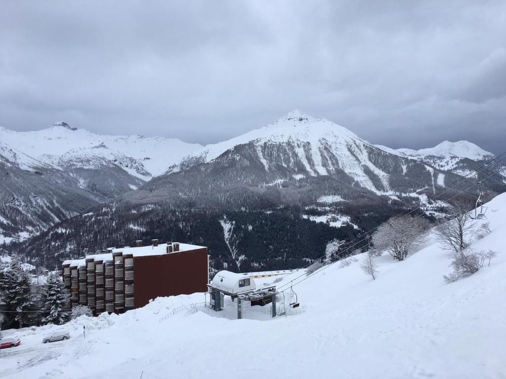 een met sneeuw bedekte berg met een gebouw op de voorgrond bij Orcieres joli studio in Orcières