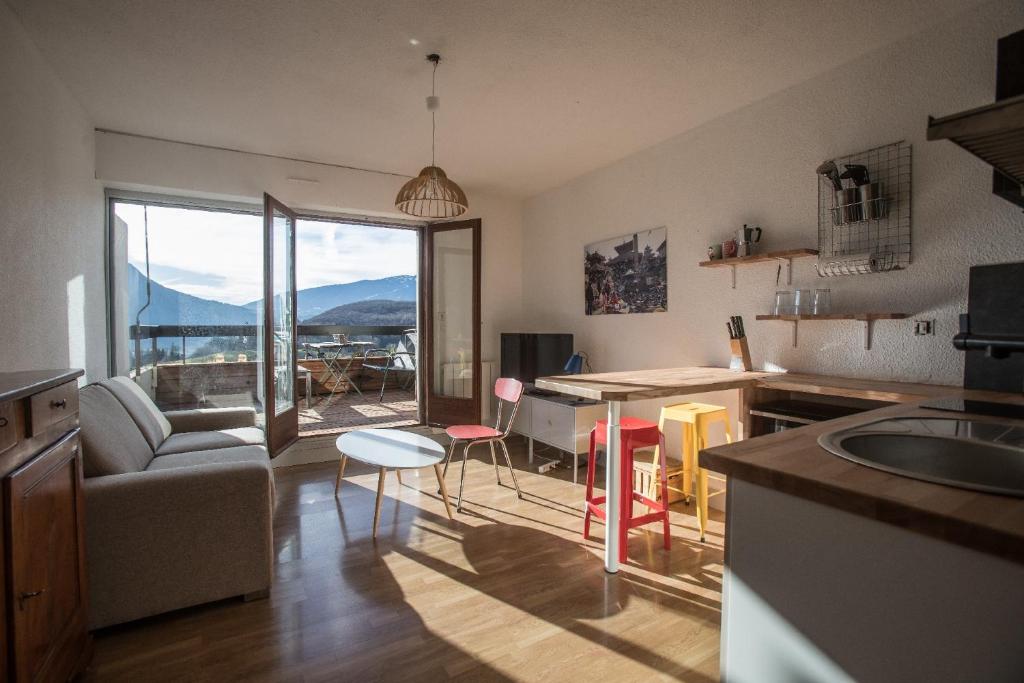 a kitchen and living room with a couch and a table at Appartement Talloires vue lac et montagnes in La Pirraz