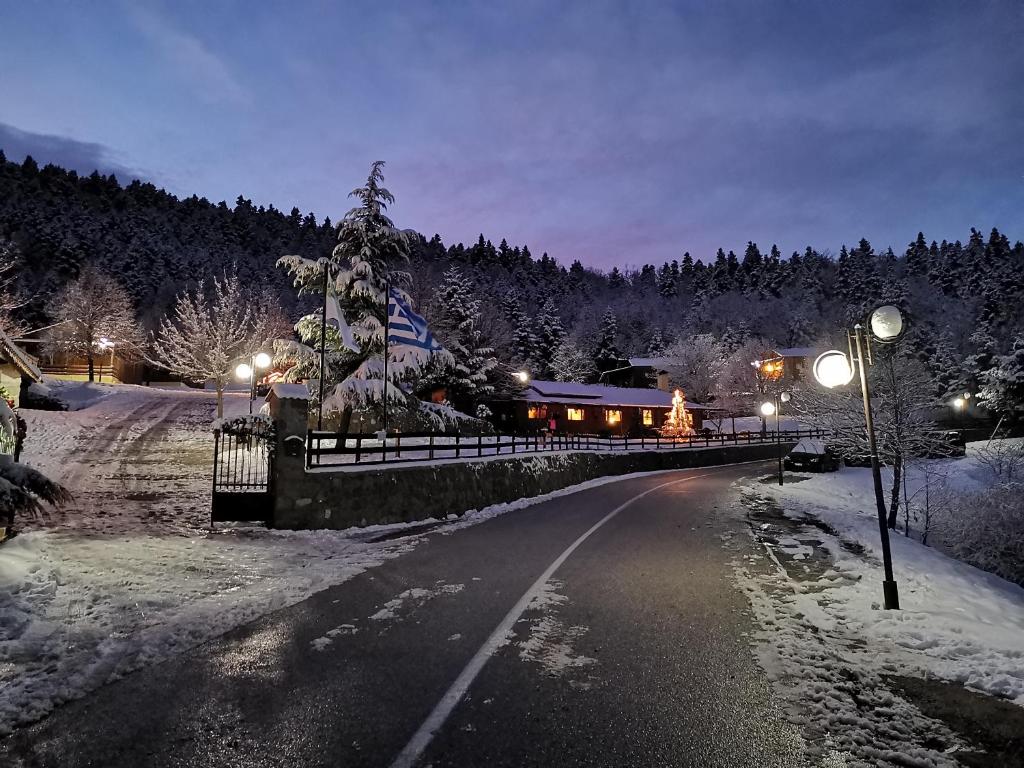 a snow covered road with a fence and street lights at Livadaki Village in Megáli Kápsi