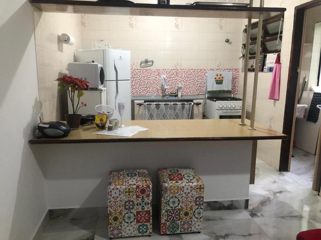 a kitchen with a counter with two stools under it at Cantinho da Lu em apt inteiro 800 mt da praia in Bertioga