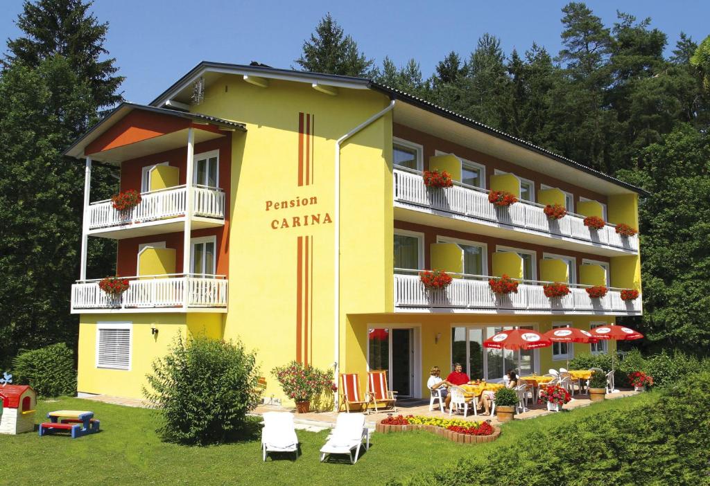un hotel amarillo con mesas y sillas frente a él en Pension Carina, en Sankt Kanzian
