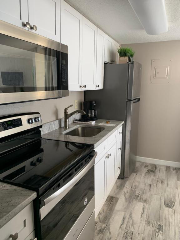 a kitchen with white cabinets and a stainless steel refrigerator at 426 Belle Vue Magnificent Oceanfront studio with two balconies in Myrtle Beach