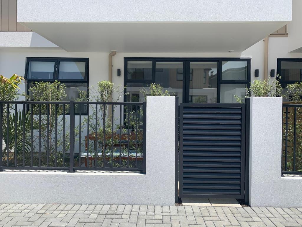 a house with a black gate and a fence at De la Plage Residences in Orewa