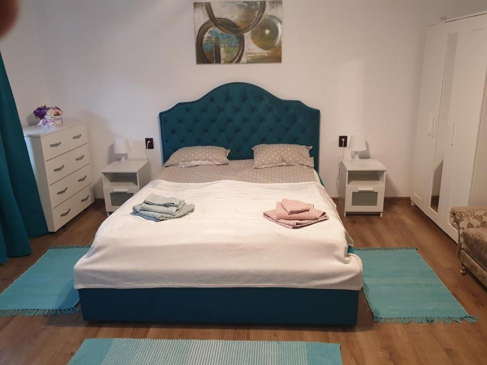 a bedroom with a bed with a blue headboard and two rugs at Garsoniera Mihaela in Onești