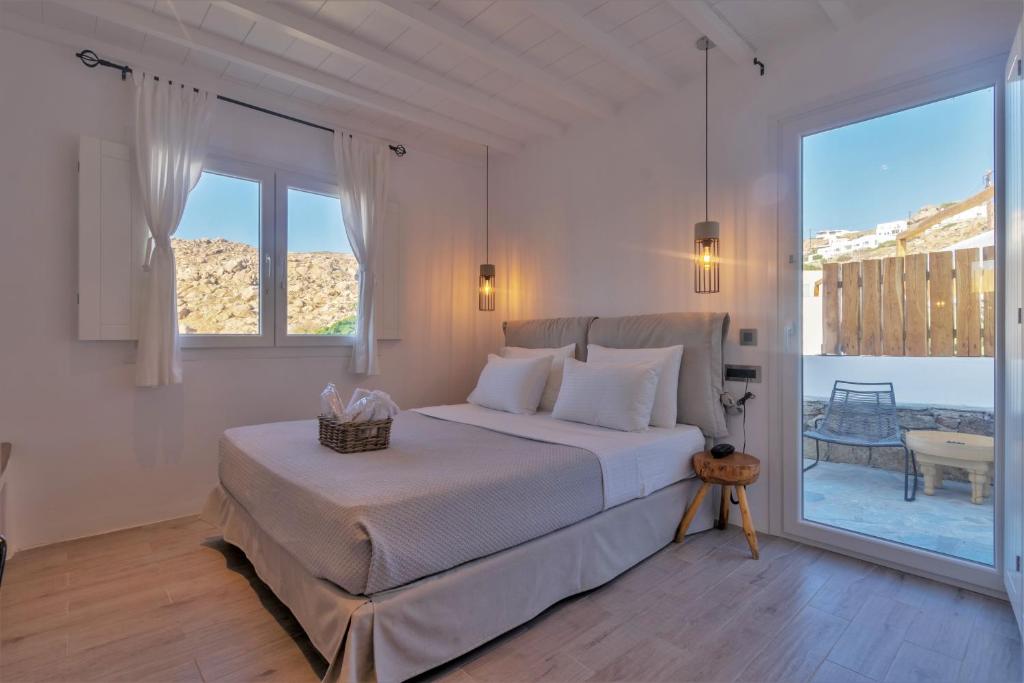 a white bedroom with a bed and a large window at Aelia Mykonos in Ornos