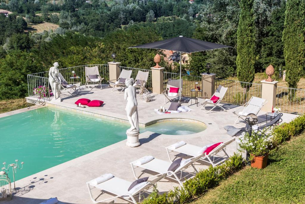 une piscine avec une statue, des chaises et un parasol dans l'établissement VILLA TURRI - Luxury Country & Padel Resort, à Camporgiano