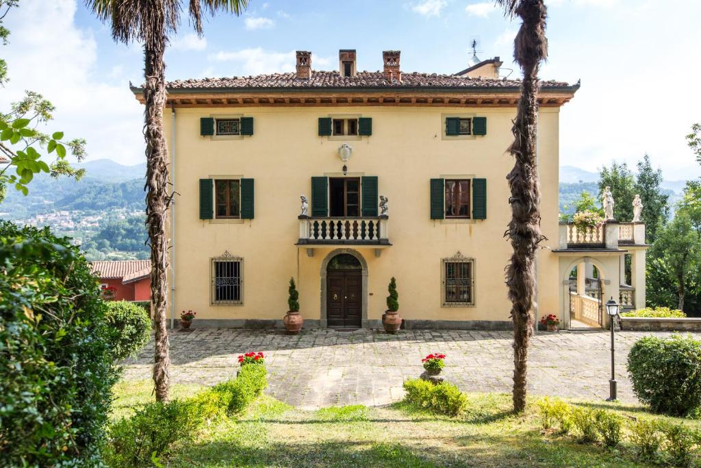 a large house with palm trees in front of it at VILLA TURRI - Luxury Country & Padel Resort in Camporgiano