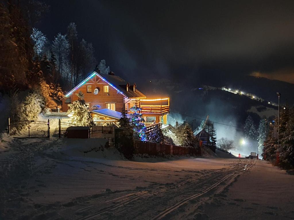 a house is decorated with christmas lights in the snow at Willa NA STOKU in Wisła