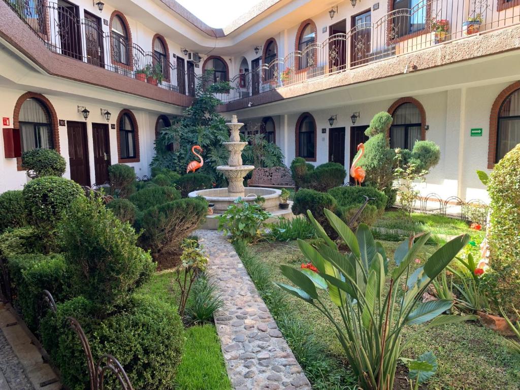 a courtyard of a building with a fountain and plants at Hotel Los Arcos in Hidalgo del Parral