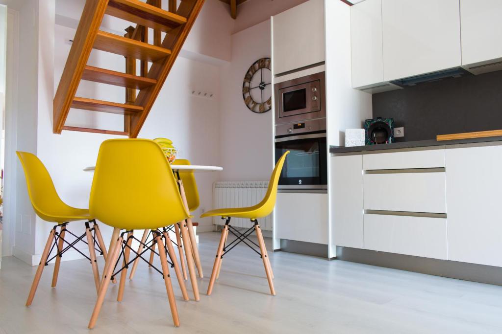 eine Küche mit gelben Stühlen und einem Tisch in der Unterkunft Lujoso y moderno dúplex con fantástica terraza in La Laguna