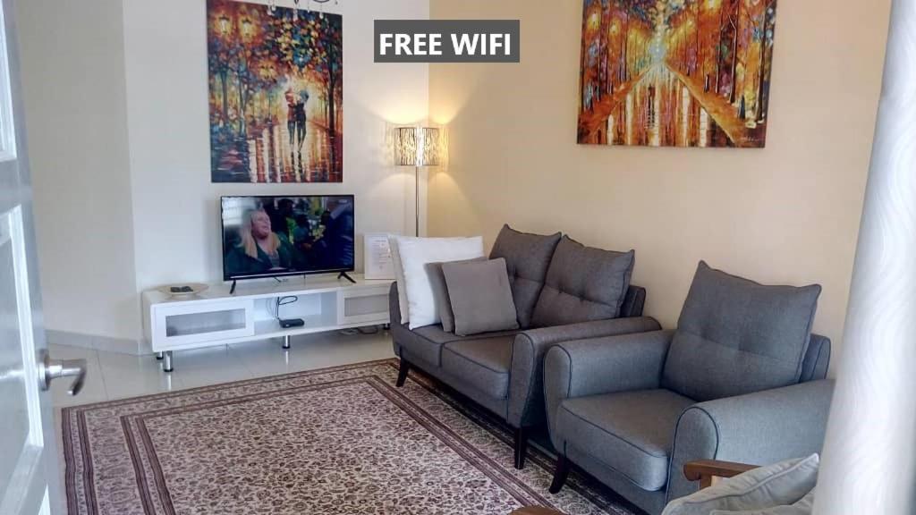 a living room with a couch and a tv at Tropicana Home Concept @ Wabest, KLIA in Sepang