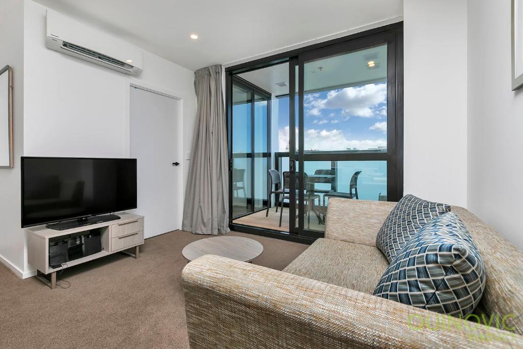 a living room with a couch and a television at QV Stays City Central Apartment with Parking in Auckland