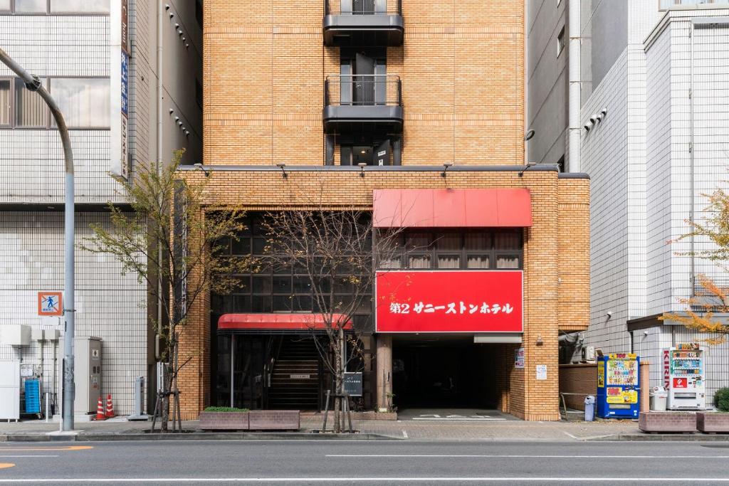 a brick building with a red sign on it at Dai-ni Sunny Stone Hotel in Osaka