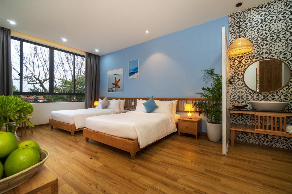 ホイアンにあるHoi An Gravel Pool Villa & Spaのベッド2台と鏡が備わるホテルルームです。