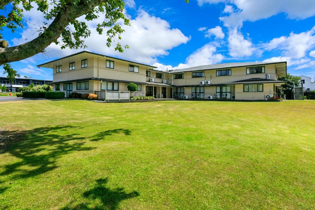 an exterior view of a large building with a large yard at Albany Oak Motel in Auckland