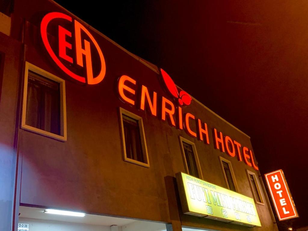 um edifício com sinais de néon vermelho na lateral em Enrich Hotel em Sungai Buluh