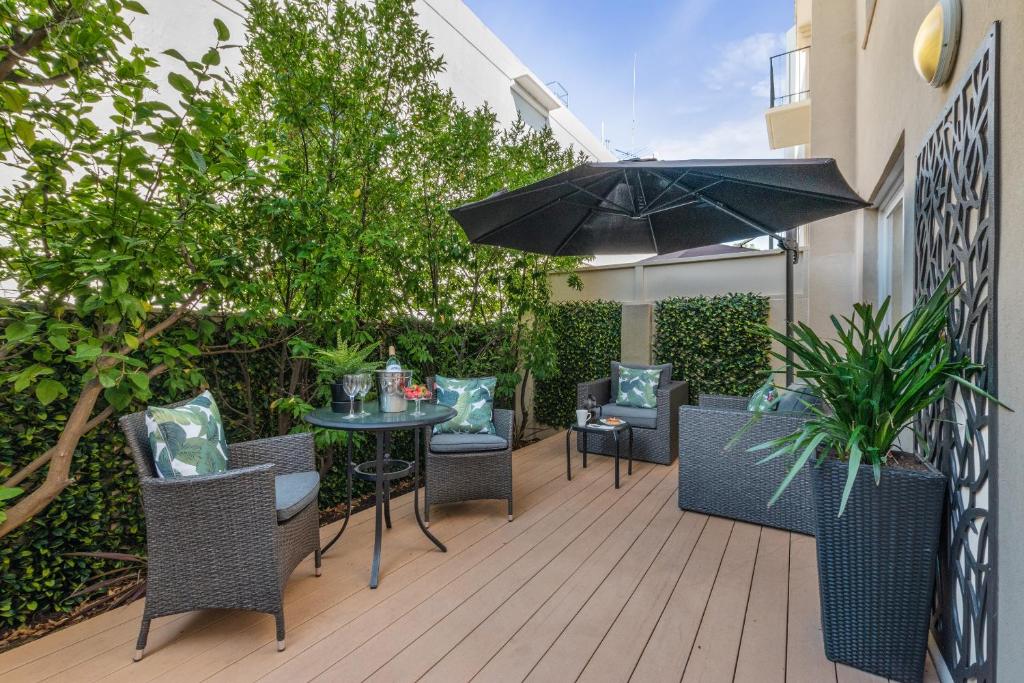 un patio con mesa, sillas y sombrilla en The Peninsula Riverside Serviced Apartments en Perth