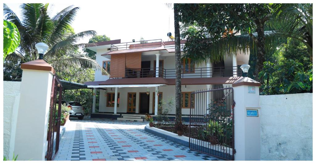 a white house with a gate and palm trees at Anand homestay in Kattappana