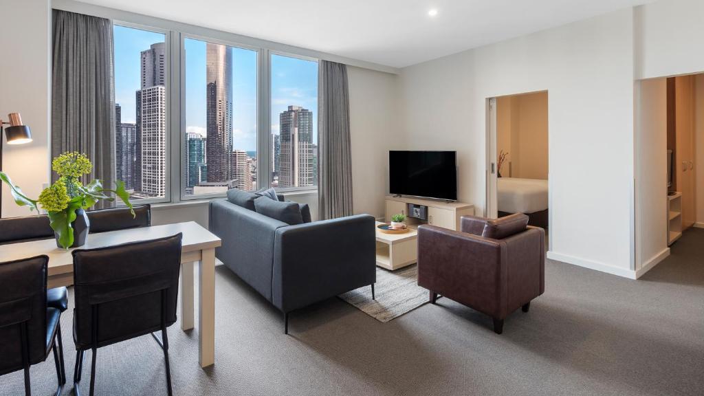 a living room with a room with a view of a city at Oaks Melbourne on Market Hotel in Melbourne