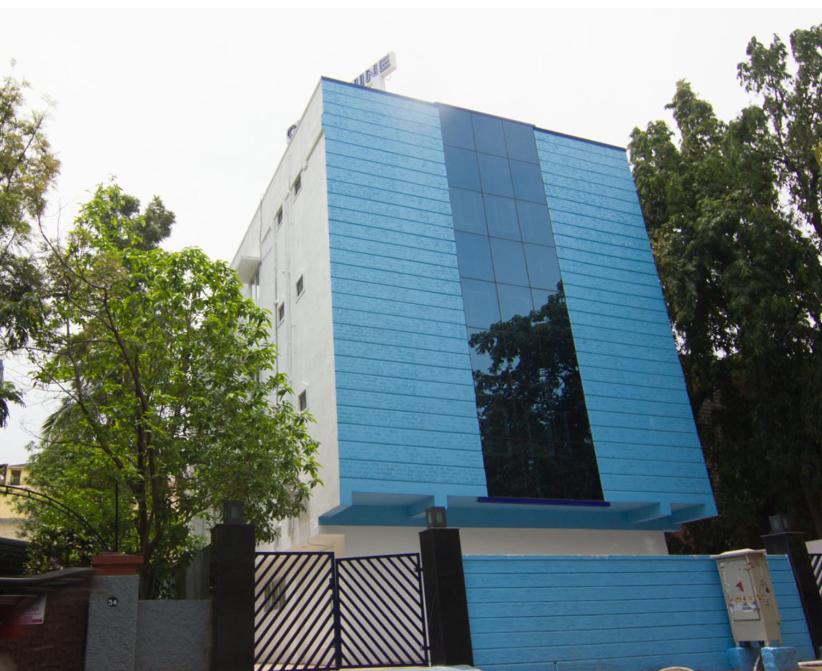 um edifício azul e branco com árvores em frente em Cloud Nine Serviced Apartments em Chennai