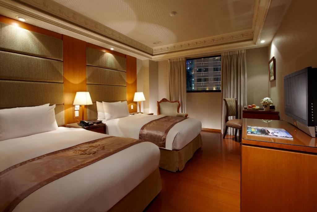 a hotel room with two beds and a flat screen tv at Deja Vu Hotel in Taipei