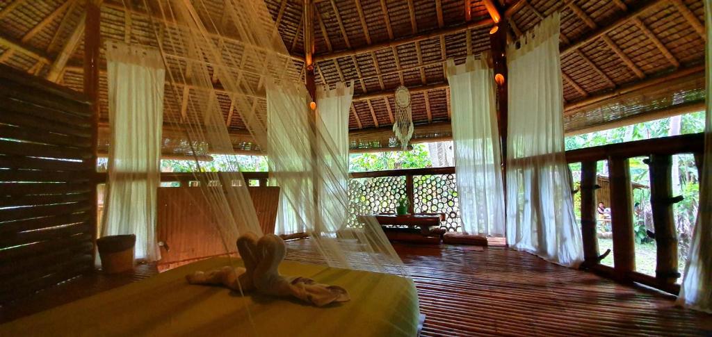 a woman laying on a bed in a room with windows at Water to Forest Ecolodge in Loboc