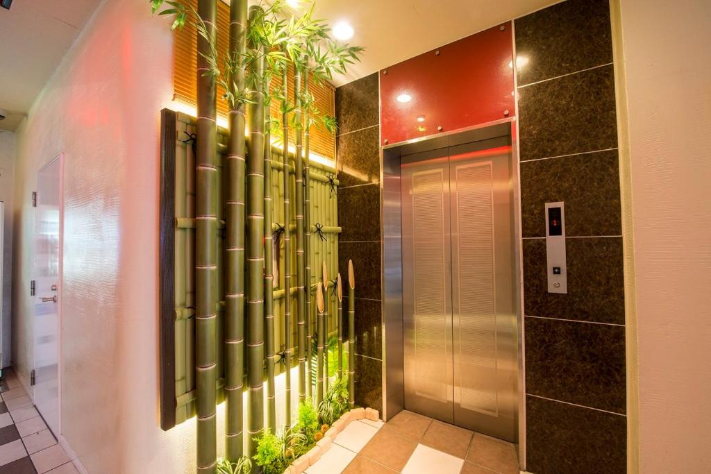 a bathroom with a shower with plants on the wall at Sejour Inn Nagarekawa in Hiroshima