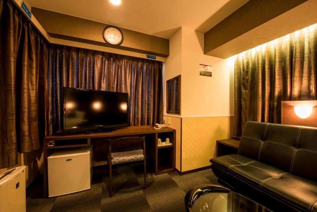 a hotel room with a couch and a television at Sejour Inn Nagarekawa in Hiroshima