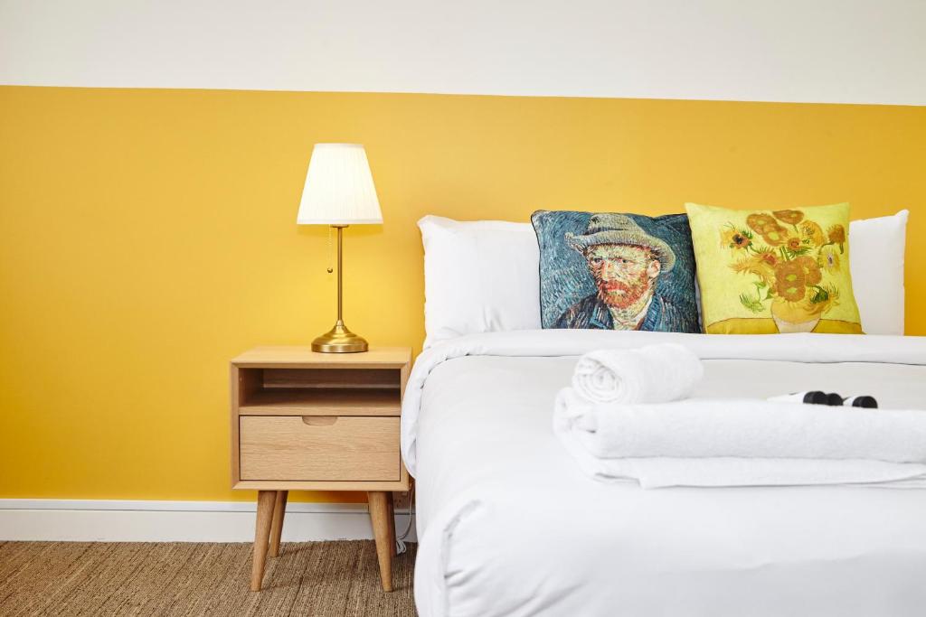 a bedroom with a bed with a yellow wall at The Erko Hotel in Sydney