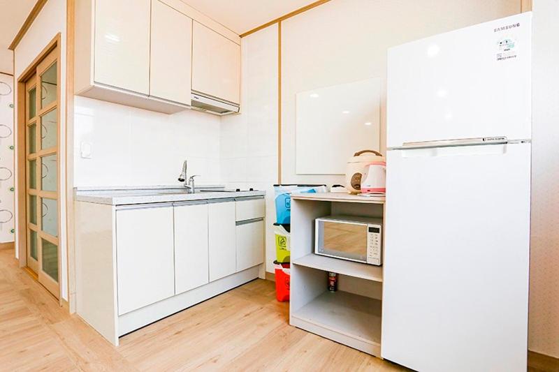 a kitchen with white cabinets and a refrigerator at Jeju Special Pension in Jeju