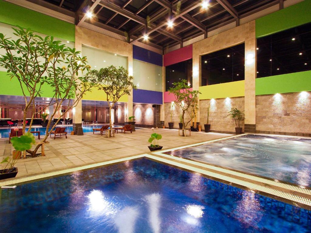 タンゲランにあるFM7 リゾートホテル ジャカルタ エアポートの植物の木造建築の大型スイミングプール