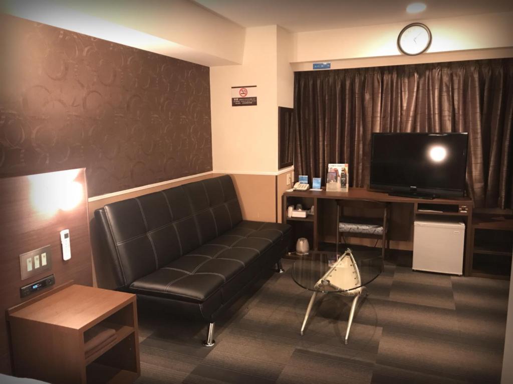 a living room with a couch and a television at Sejour Inn Nagarekawa in Hiroshima