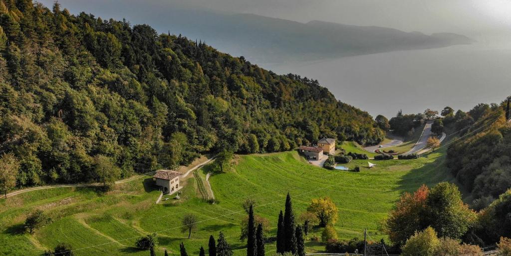 ein grünes Feld mit einem Haus an der Seite eines Hügels in der Unterkunft Borgo Paradiso in Tignale