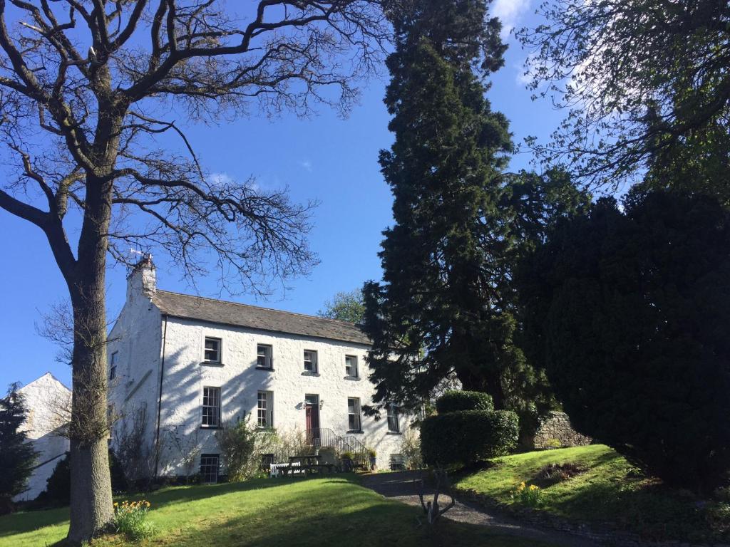 Una casa blanca con un árbol delante. en Lowbyer Manor Country House, en Alston