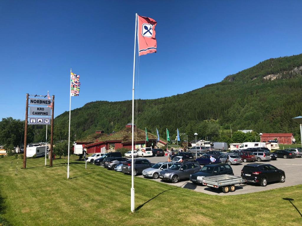 un estacionamiento con una bandera y coches estacionados en Nordnes Kro og Camping, en Rokland