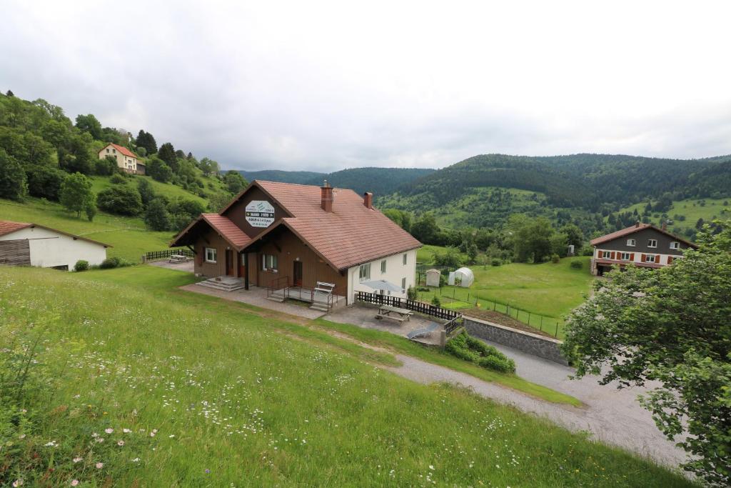 una casa en una colina con un campo verde en Les Chantenées, en La Bresse