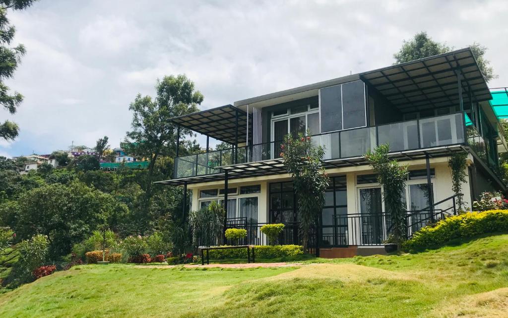 a house on top of a grassy hill at Sunvalley Homestay in Coonoor