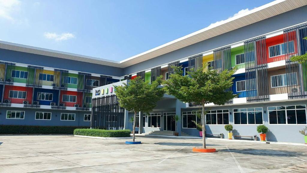 un bâtiment coloré avec des arbres devant lui dans l'établissement Bun Hotel, à Surat Thani