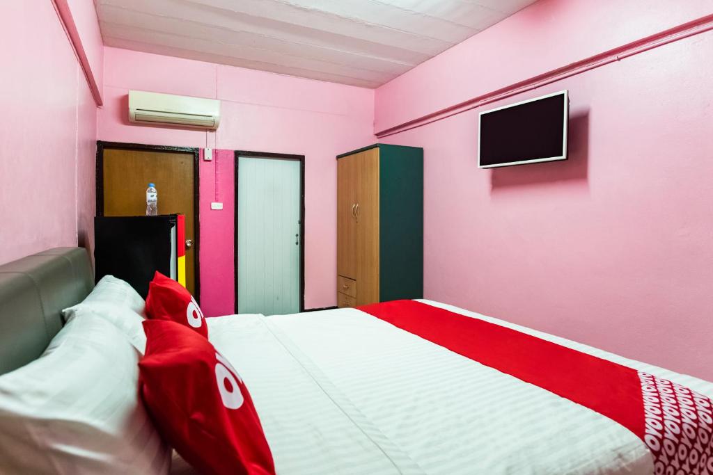 Habitación de color rosa y blanco con cama y TV. en Gedkanok Apartment, en Bangkok