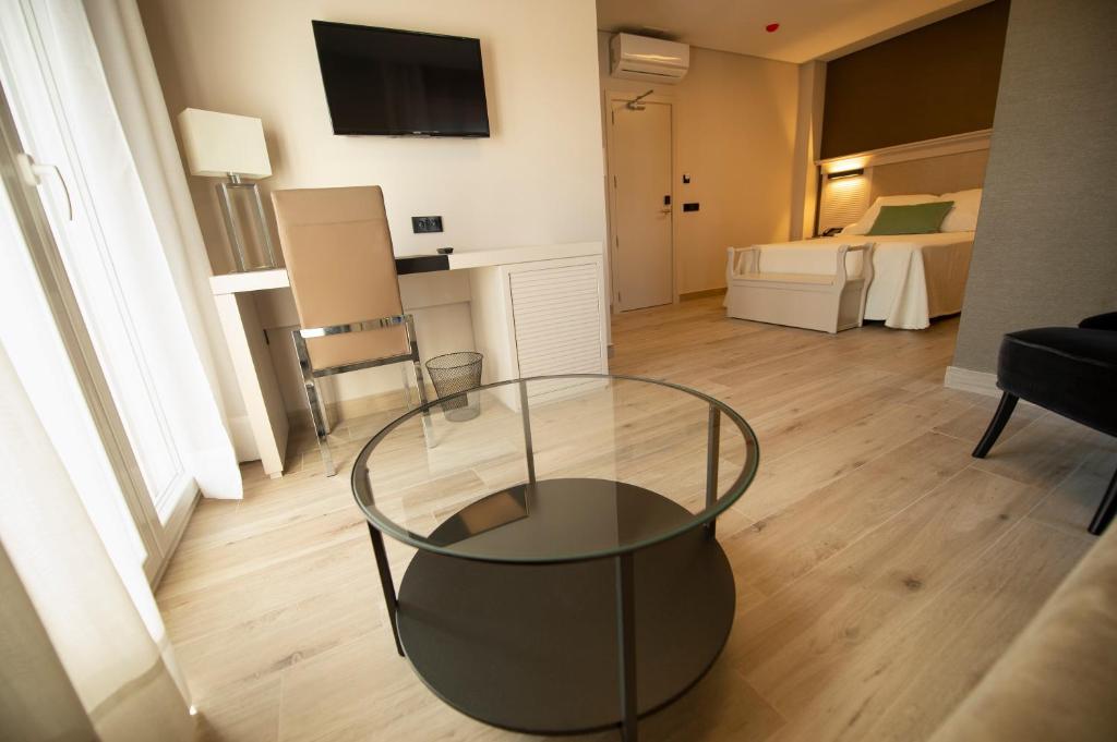 a living room with a glass table and a bedroom at Hotel Diufain in Conil de la Frontera