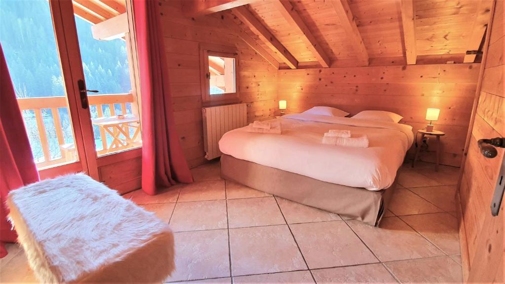 um quarto com uma cama num chalé de madeira em Bienvenue dans notre chalet! Appartement Les Sitelles em Le Grand-Bornand