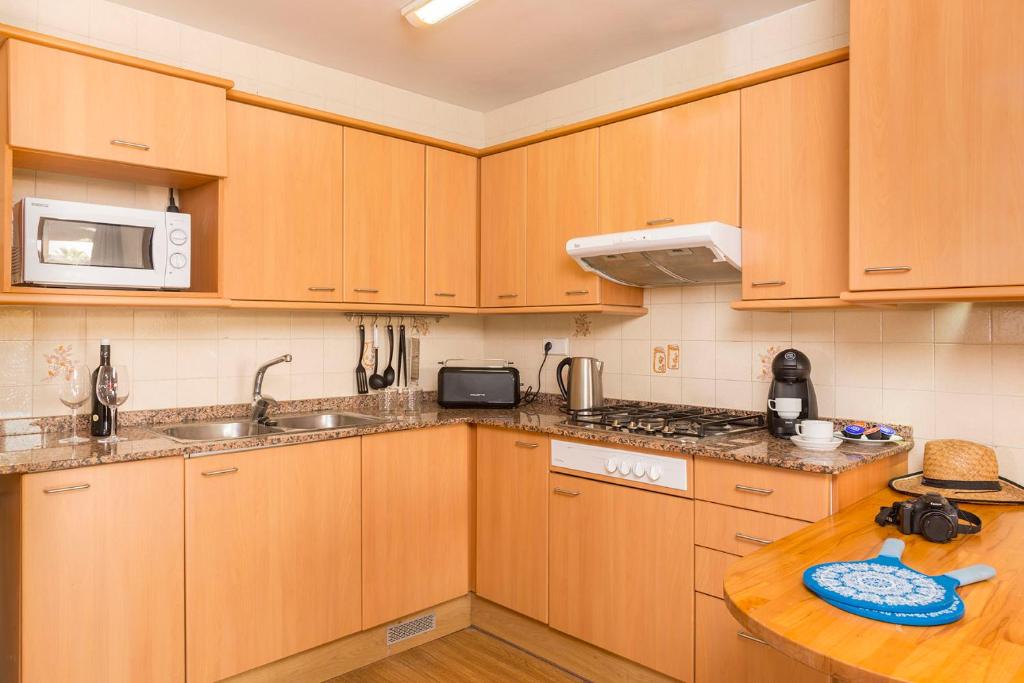 a kitchen with wooden cabinets and a wooden table at Apartaments Els Llorers in Lloret de Mar