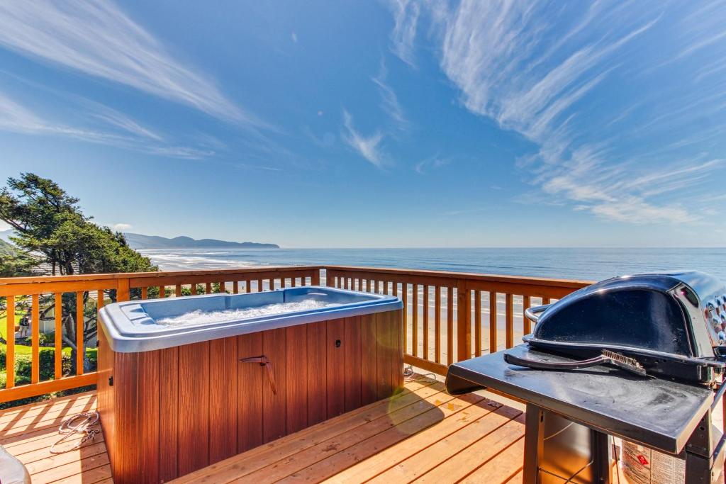 a hot tub on a deck with the ocean in the background at Blue Sea Oceanfront Cottage in Oceanside
