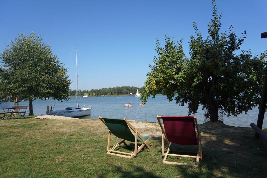 two chairs sitting on the grass near the water at Mazurska Zagroda in Rydzewo