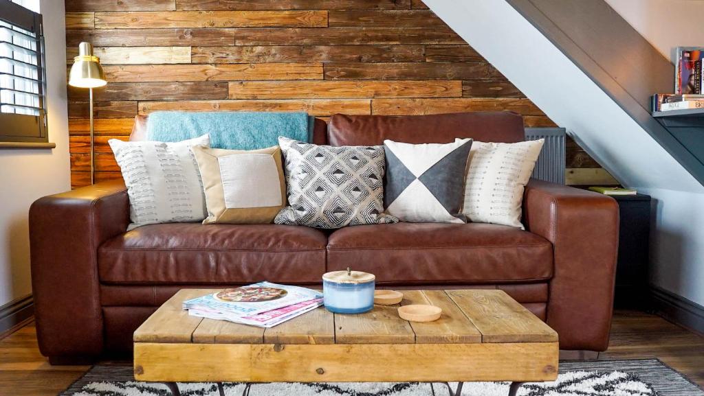 a brown leather couch with pillows and a coffee table at By the Way in Great Malvern