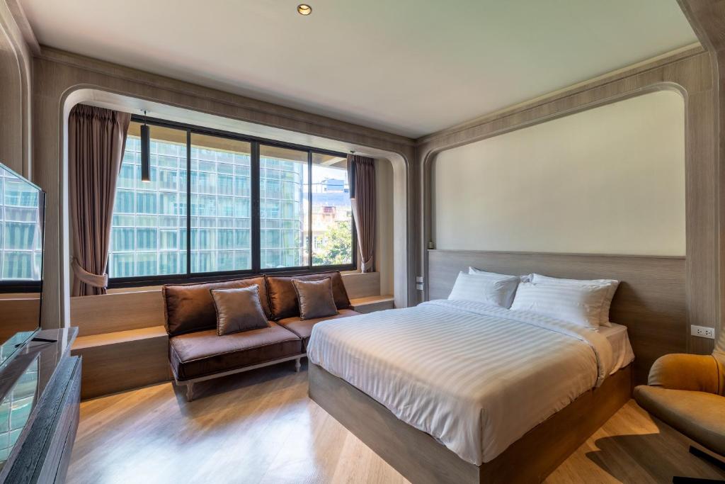 um quarto com uma cama, um sofá e uma janela em The Spades Private Residence em Bangkok