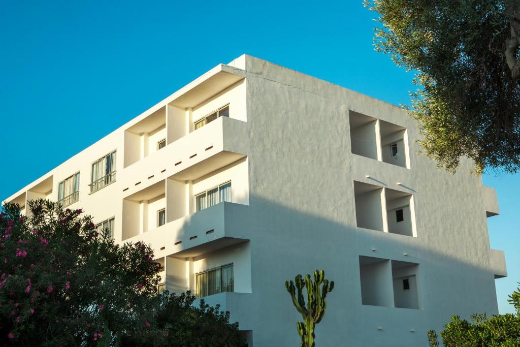 um edifício branco com árvores em frente em Apartamentos Maria - Formentera Vacaciones em Es Pujols