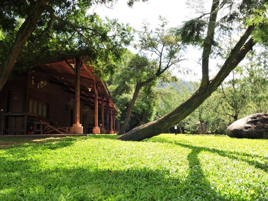 a house in the middle of a field of grass at Zen and Pine Resort in Shuili