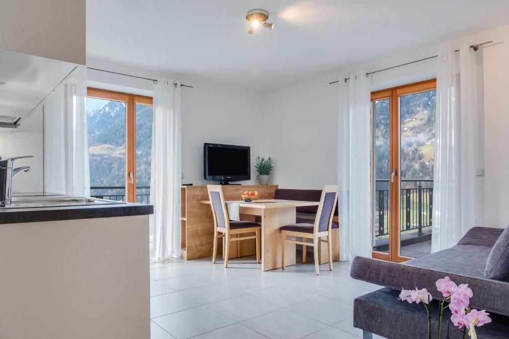 een keuken en een woonkamer met een tafel en een bank bij Hofschenke Pfeiftal - Bergblick in San Martino